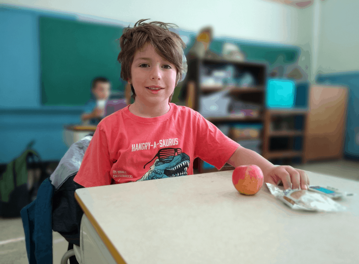 child sitting at desk with an apple